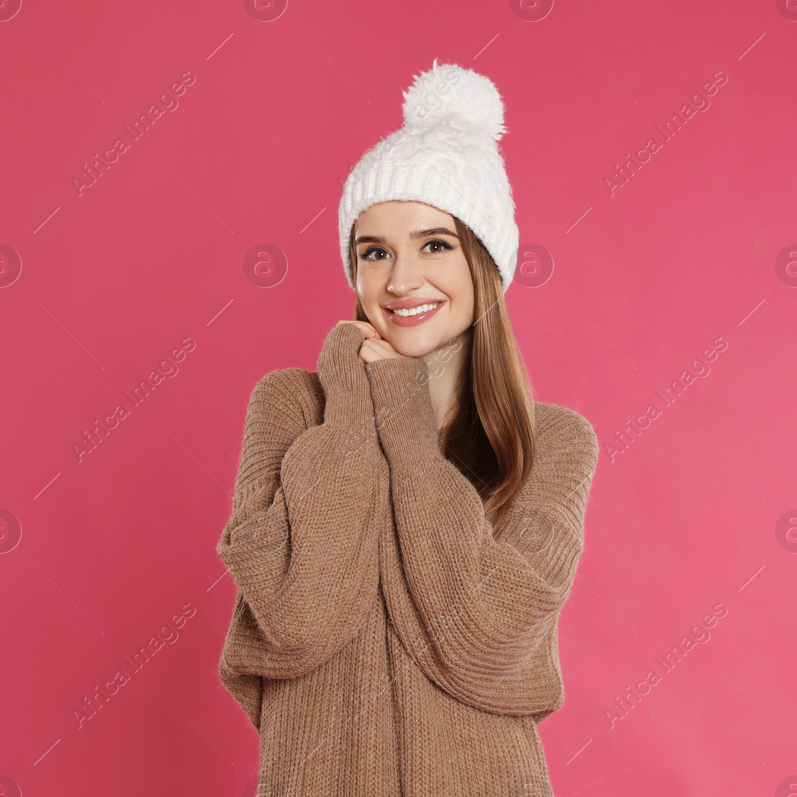 Photo of Beautiful young woman in hat and sweater on pink background. Winter season