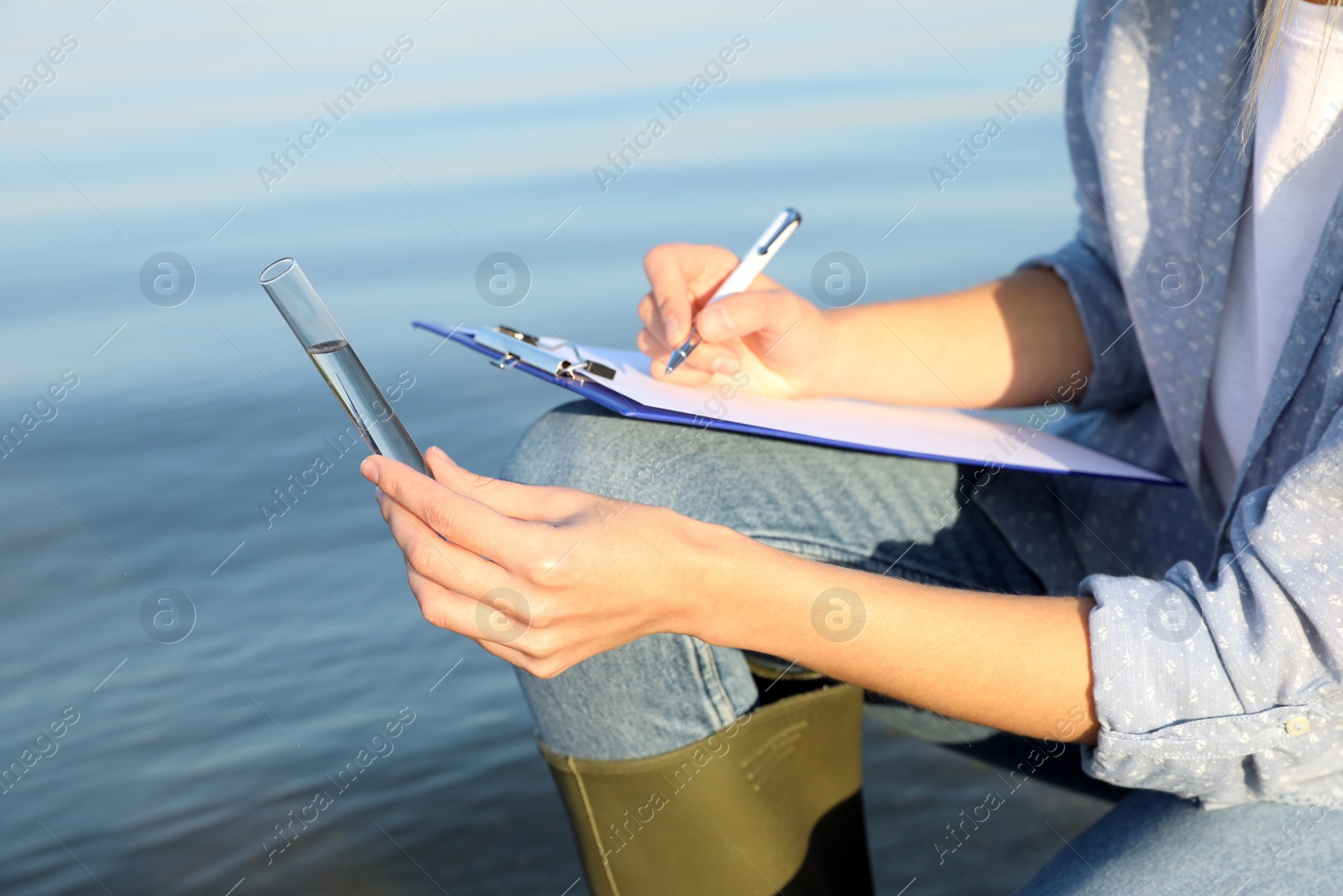 Photo of Scientist with clipboard and sample taken from river, closeup