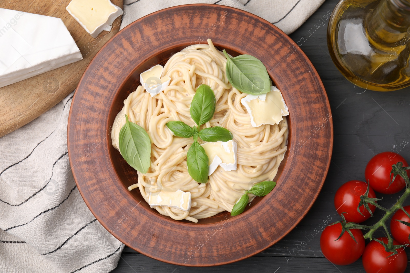 Photo of Delicious pasta with brie cheese and products on grey wooden table, flat lay