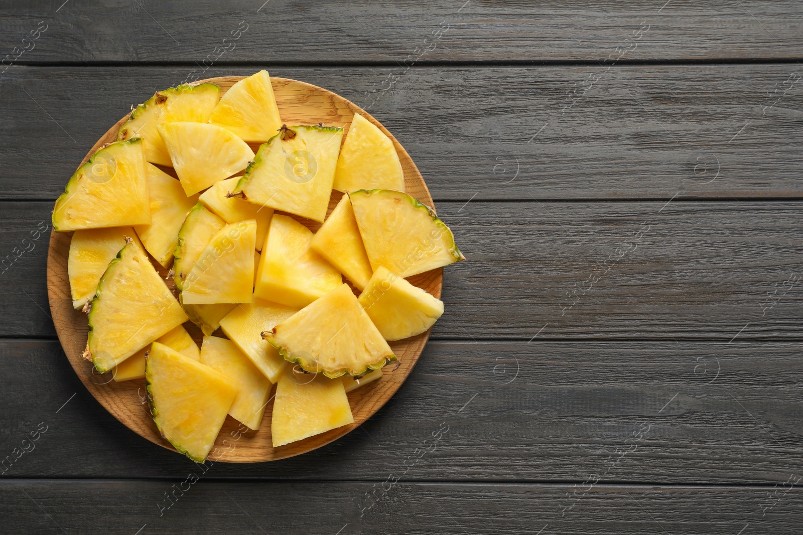 Photo of Plate with fresh sliced pineapple on wooden background