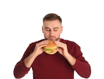 Young man eating tasty burger on white background