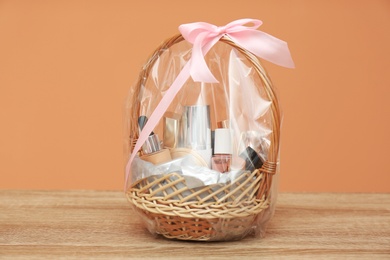 Photo of Wicker gift basket with cosmetic products on wooden table