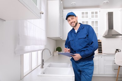 Professional plumber with clipboard checking water tap in kitchen