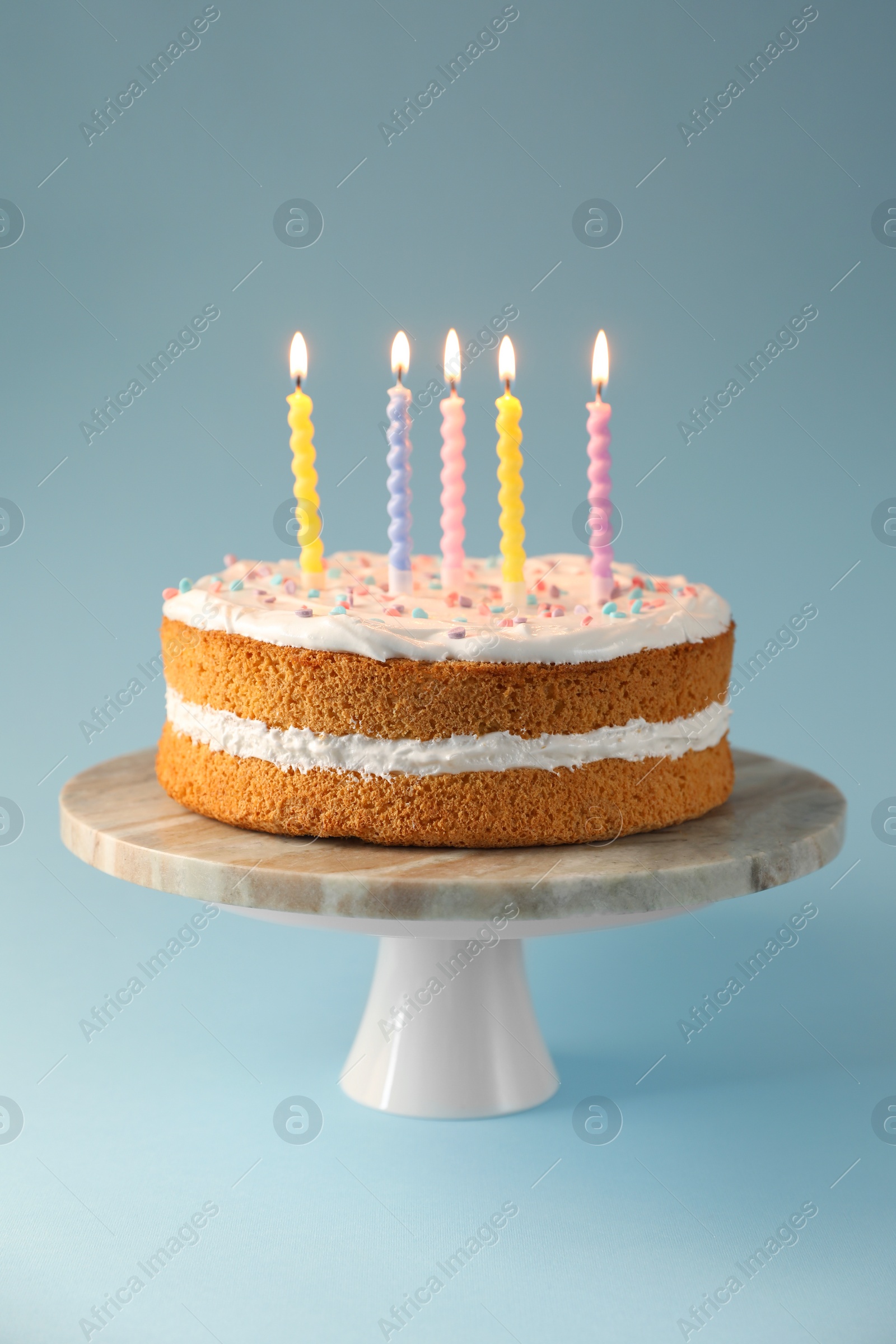 Photo of Tasty cake with colorful candles on light blue background