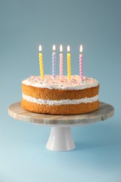 Photo of Tasty cake with colorful candles on light blue background