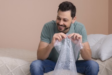 Man popping bubble wrap in bedroom at home. Stress relief