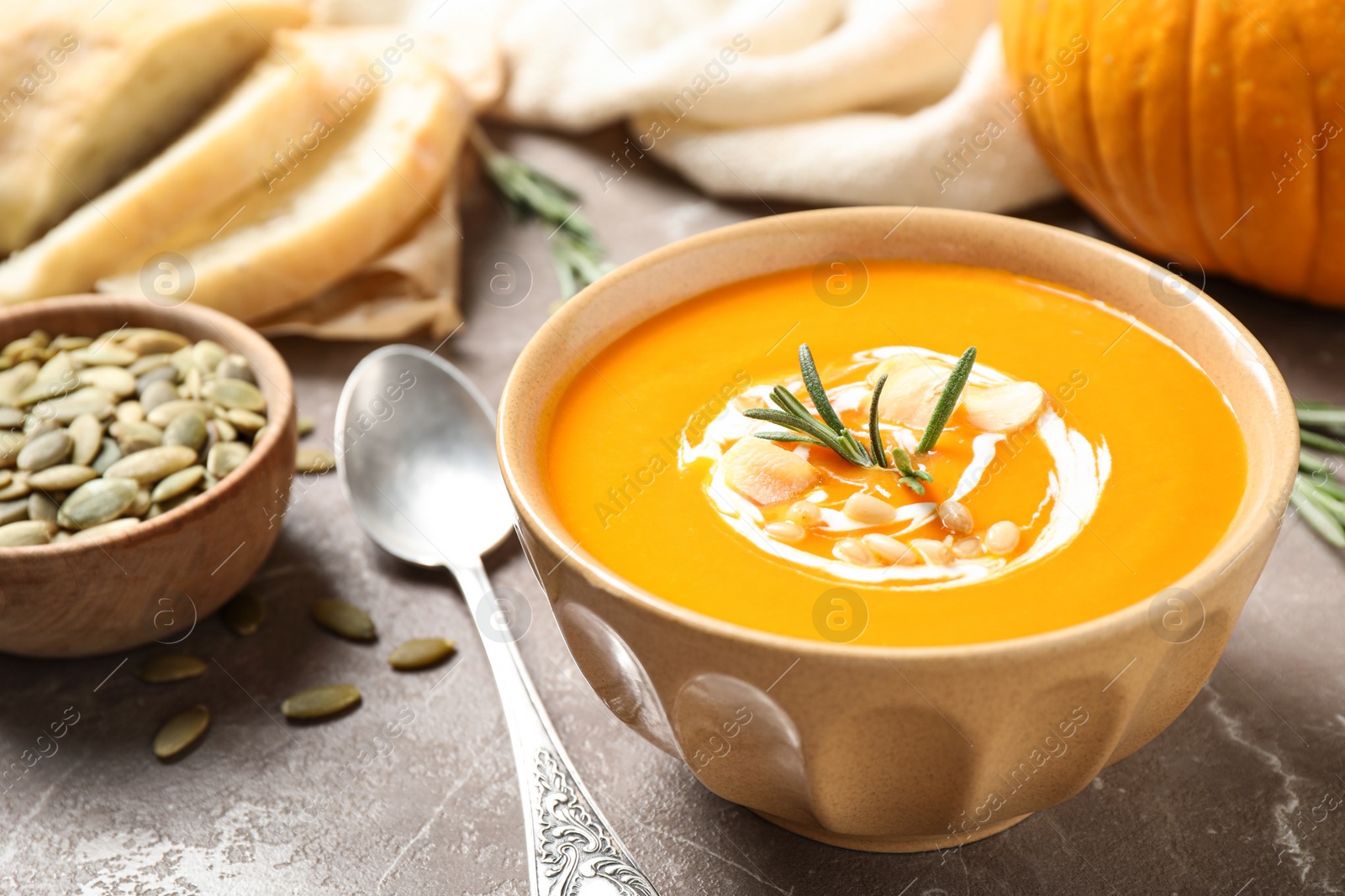 Photo of Delicious pumpkin soup in bowl on marble table