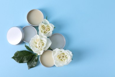 Photo of Different lip balms and rose flowers on light blue background, flat lay. Space for text