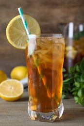 Photo of Delicious iced tea in glass on wooden table, closeup