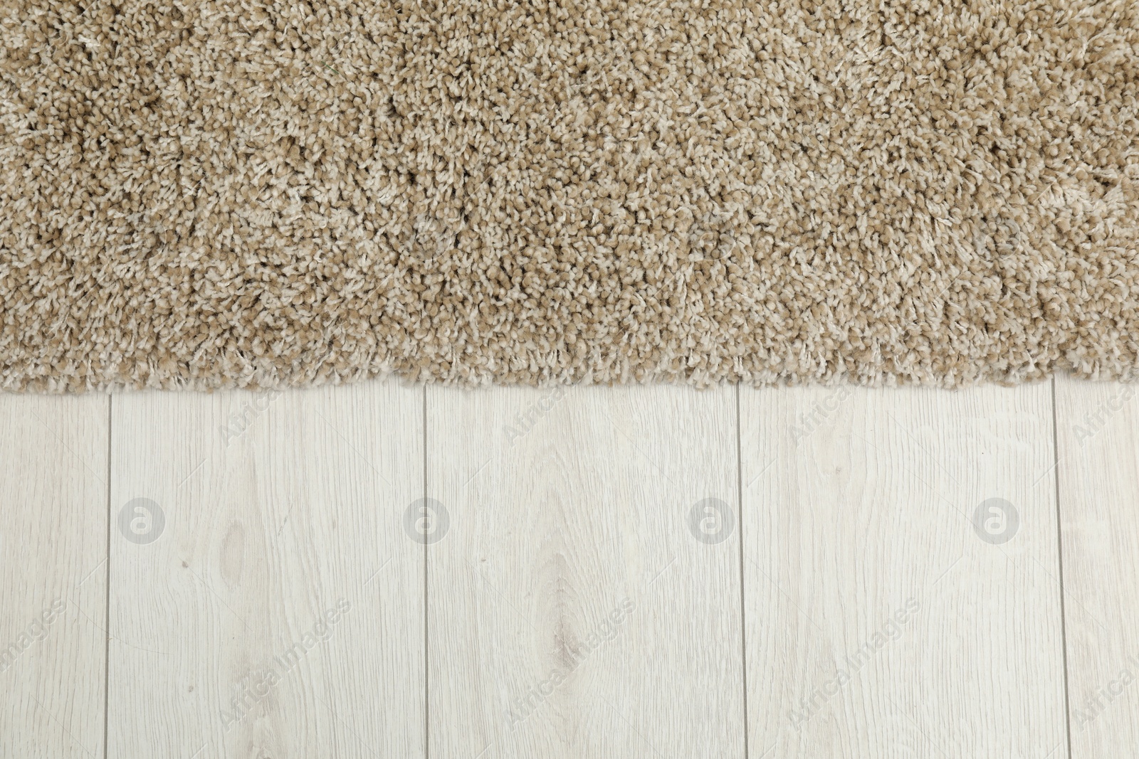 Photo of Soft beige carpet on white laminated floor indoors, top view. Space for text