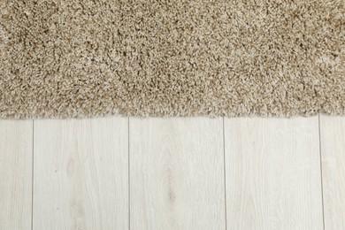 Photo of Soft beige carpet on white laminated floor indoors, top view. Space for text