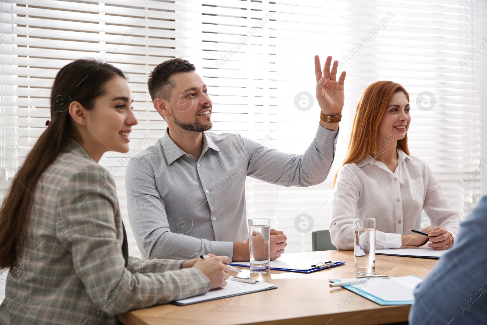 Photo of Man raising hand to ask question at business training in conference room