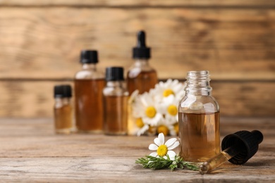 Photo of Composition with bottle of chamomile essential oil on table. Space for text