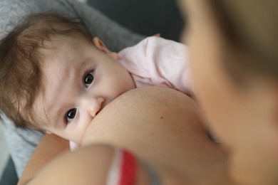 Photo of Young woman breastfeeding her baby at home, closeup