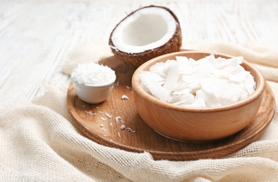 Fresh coconut flakes in bowls on wooden background