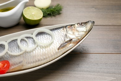 Delicious salted herring and ingredients on wooden table, closeup