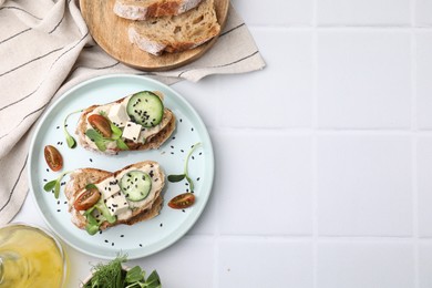 Tasty vegan sandwiches with tofu, cucumber, tomato and sesame seeds on white tiled table, flat lay. Space for text