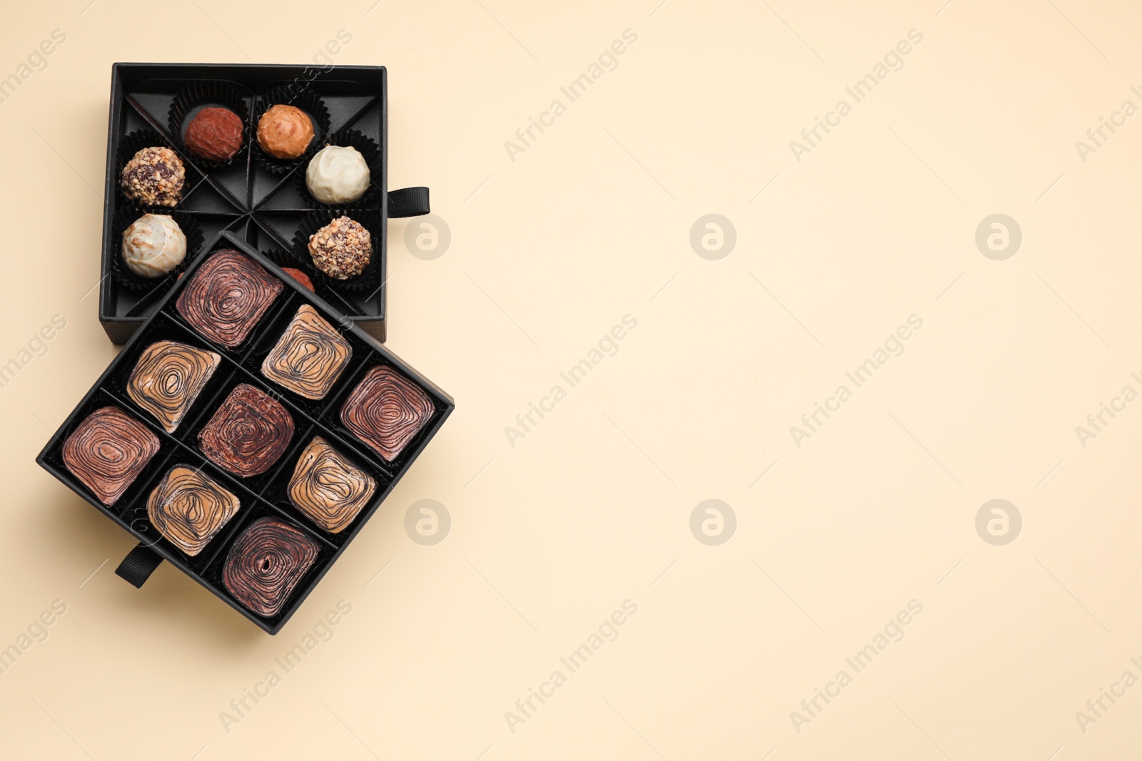 Photo of Boxes of tasty chocolate candies on beige background, flat lay. Space for text