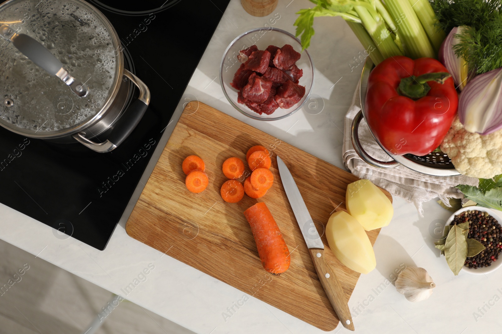 Photo of Homemade bouillon recipe. Fresh ingredients on countertop near cooktop, flat lay