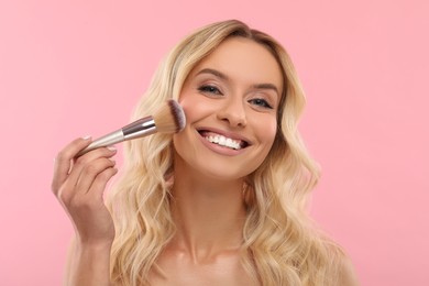 Photo of Beautiful makeup. Smiling woman with brush on pink background