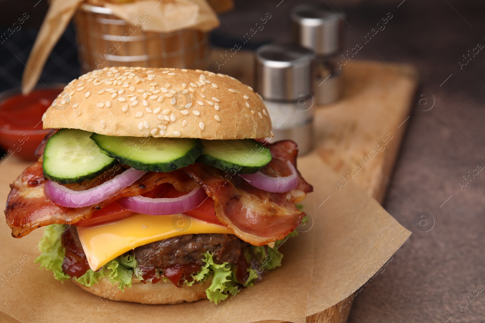 Photo of Tasty burger with bacon, vegetables and patty on textured table, closeup. Space for text