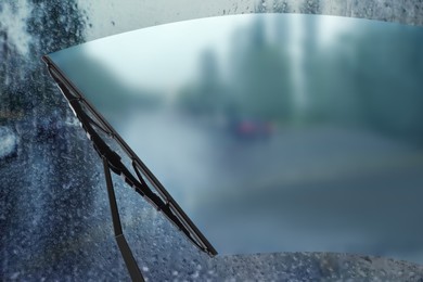 Image of Car windshield wiper cleaning water drops from glass while driving