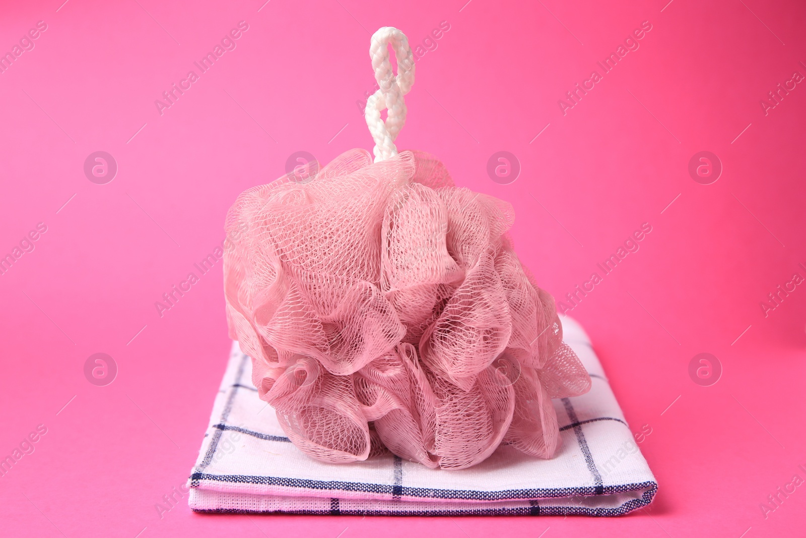 Photo of New shower puff and towel on pink background