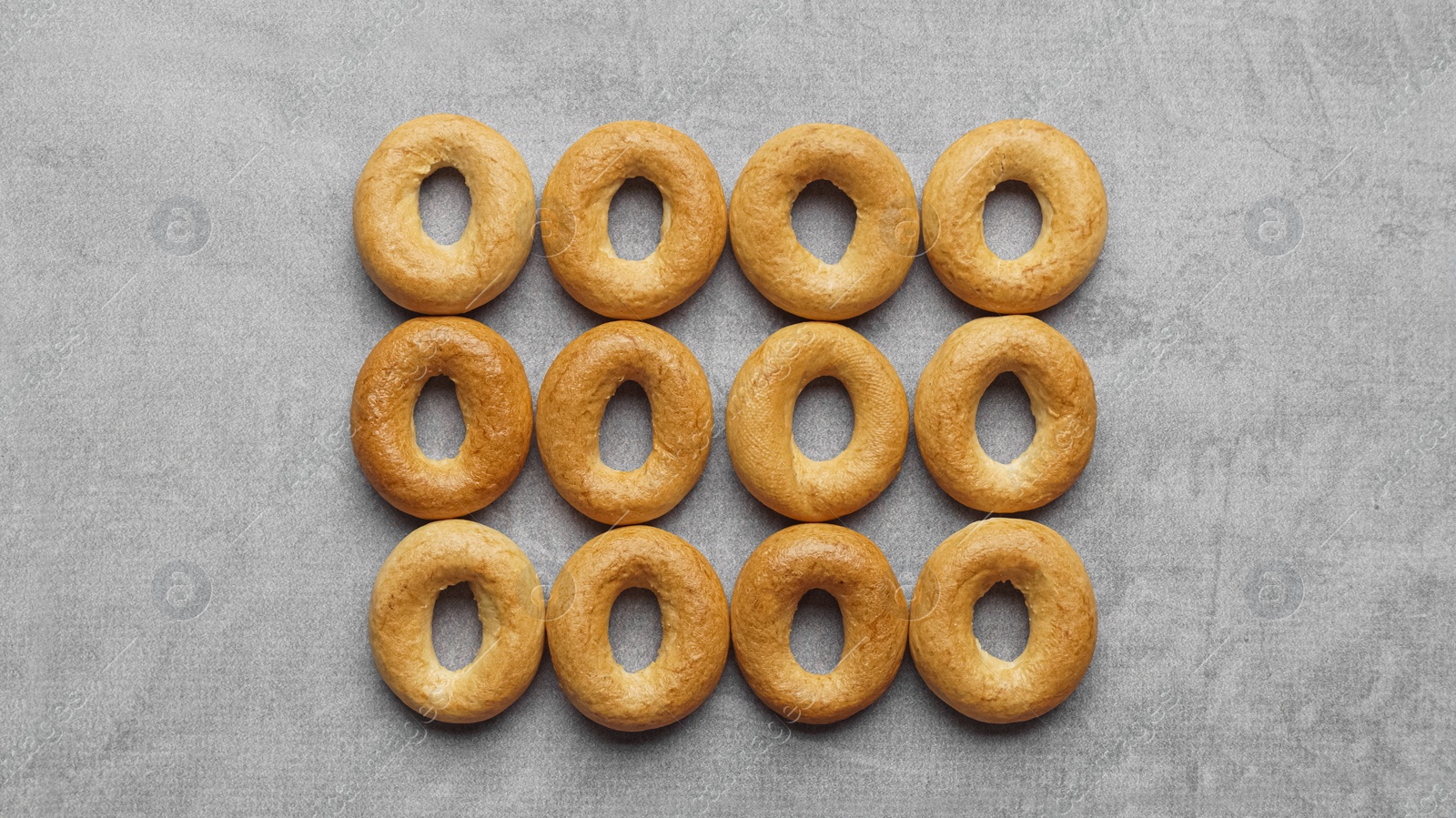 Photo of Many tasty dry bagels (sushki) on grey table, flat lay