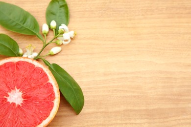 Photo of Cut fresh ripe grapefruit and green leaves on wooden table, above view. Space for text