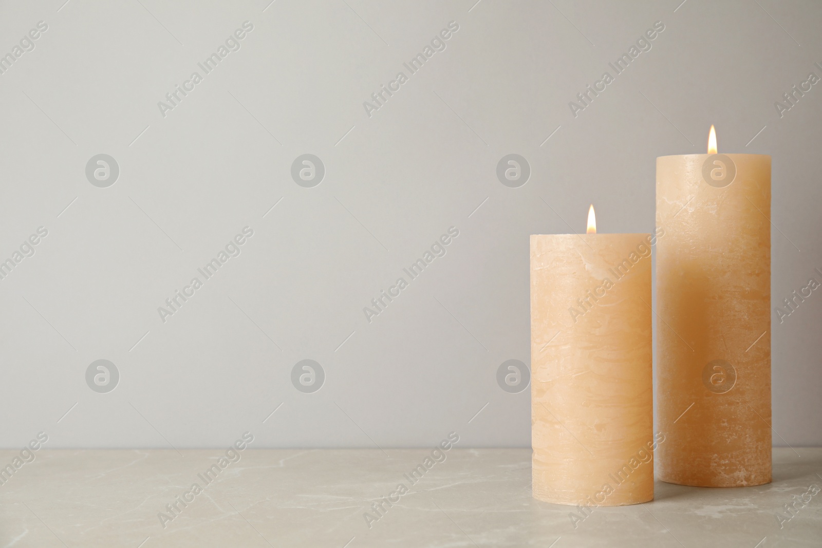 Photo of Burning candles on table against light background. Space for text