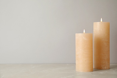 Burning candles on table against light background. Space for text