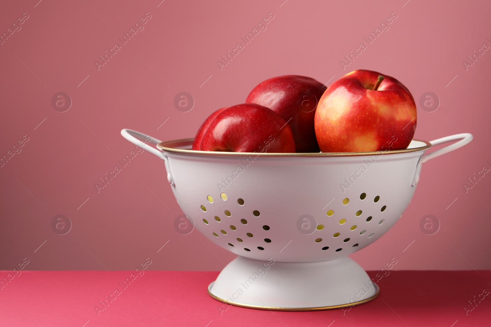 Photo of Colander with fresh apples on color background