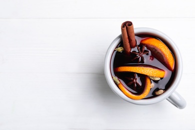 Photo of Aromatic mulled wine on white wooden table, top view. Space for text