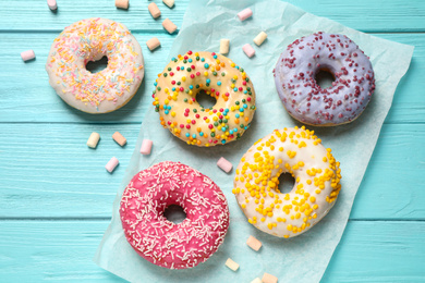 Delicious glazed donuts on blue wooden table, flat lay