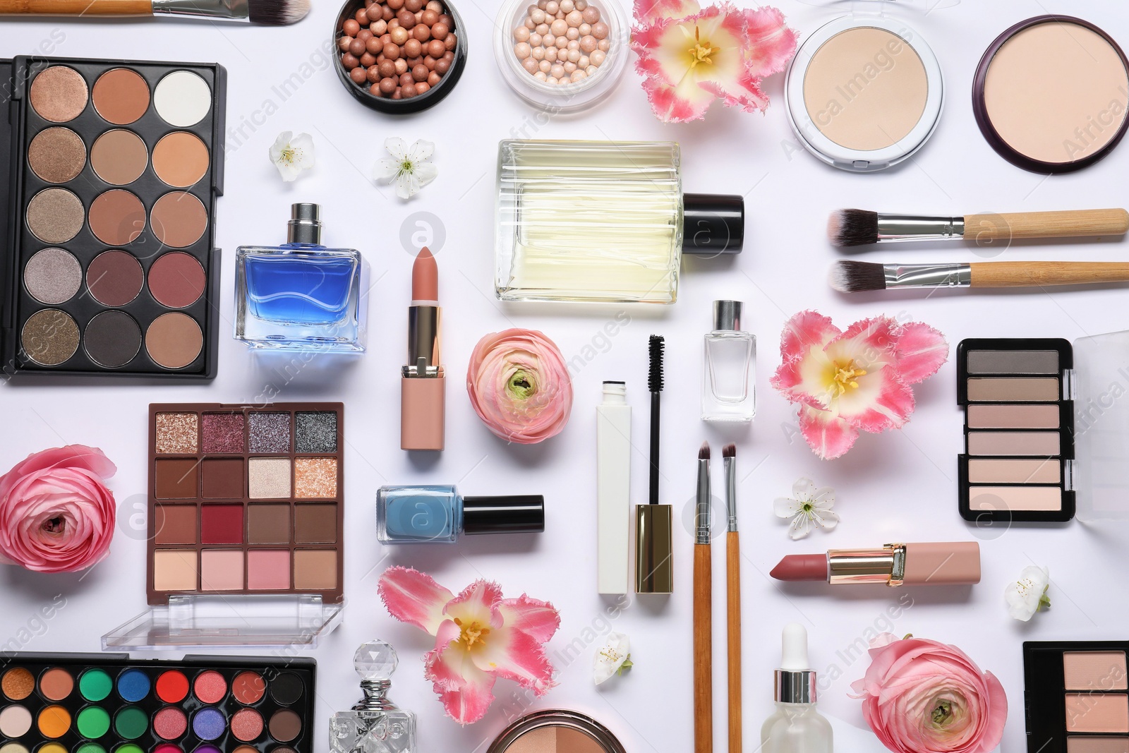 Photo of Flat lay composition with different makeup products and beautiful spring flowers on white background