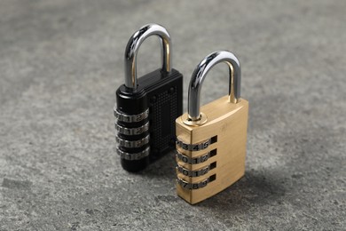 Locked steel combination padlocks on grey stone table, closeup