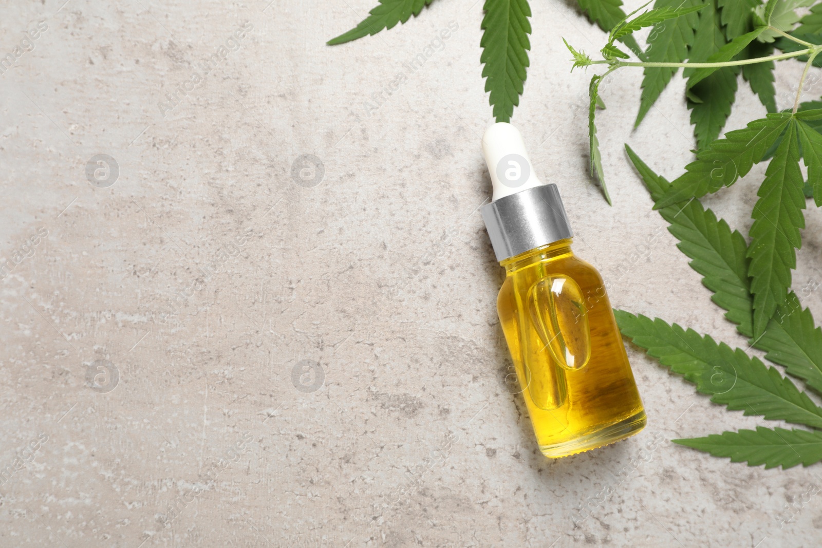 Photo of Hemp oil and leaves on light grey background, flat lay. Space for text