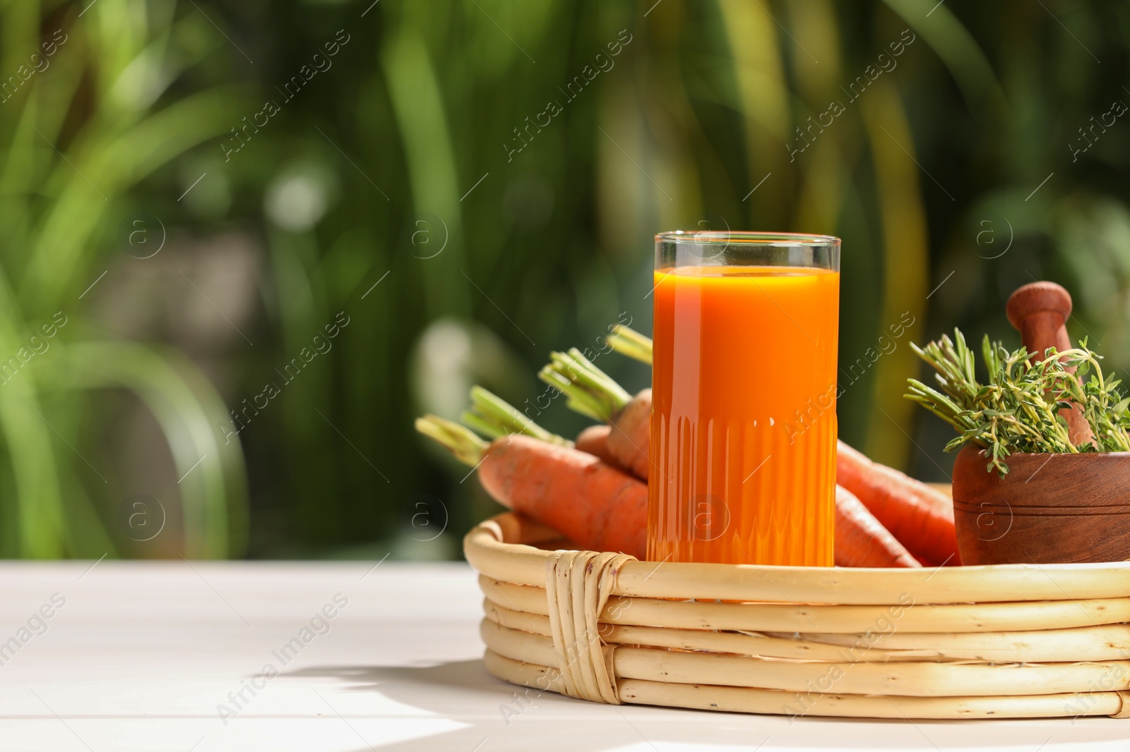 Photo of Tasty juice and ingredients on white table outdoors, space for text