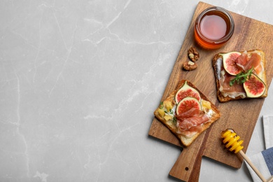 Photo of Delicious sandwiches with figs, proscuitto and cheese on light table, top view. Space for text