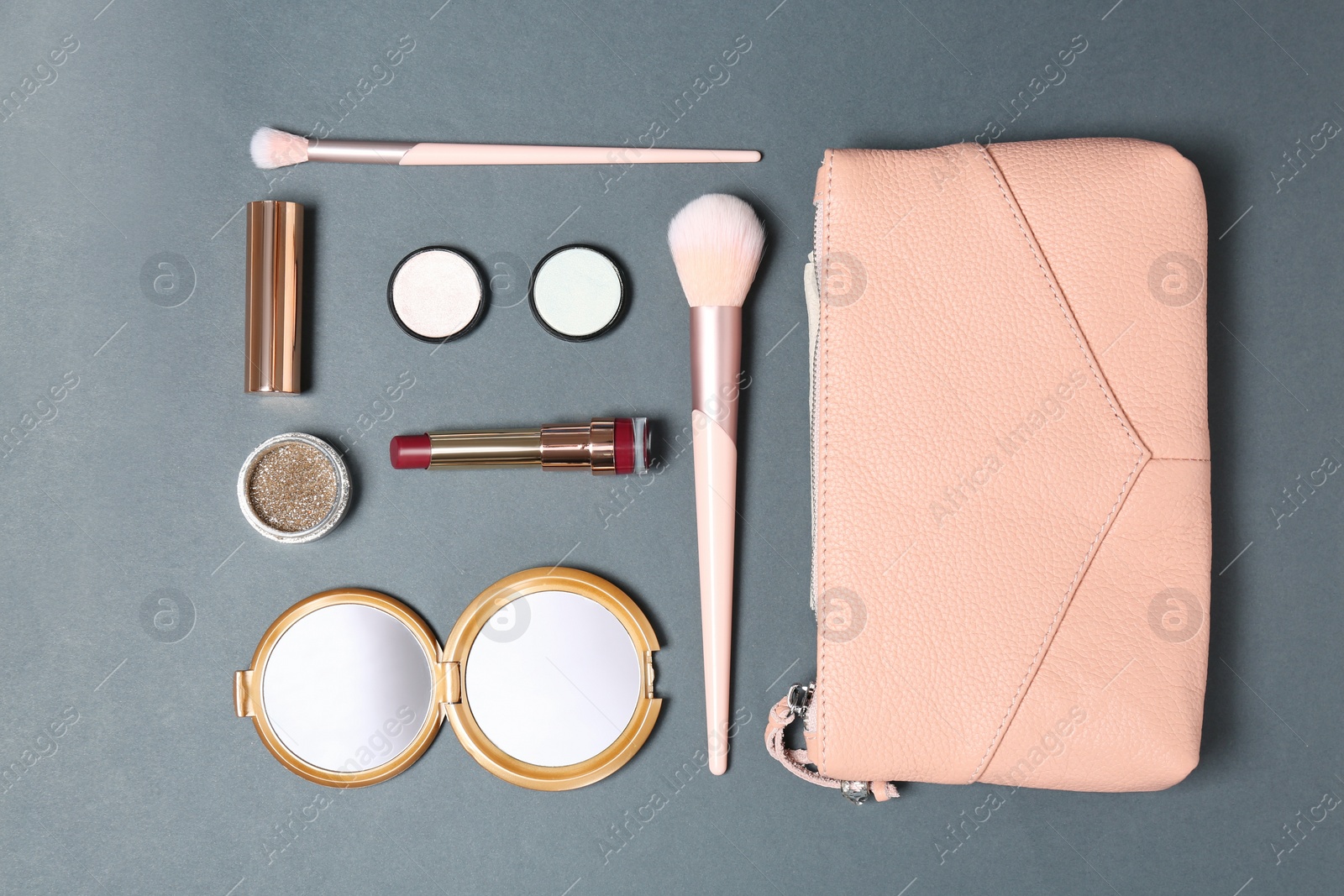 Photo of Cosmetic bag with makeup products on grey background, flat lay