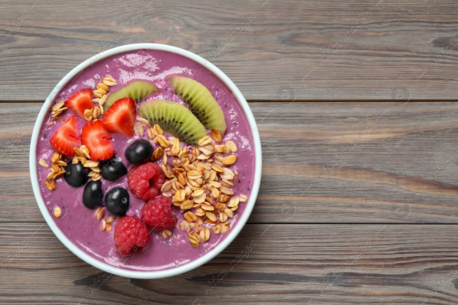 Photo of Delicious acai smoothie with fruits on grey wooden table, top view. Space for text
