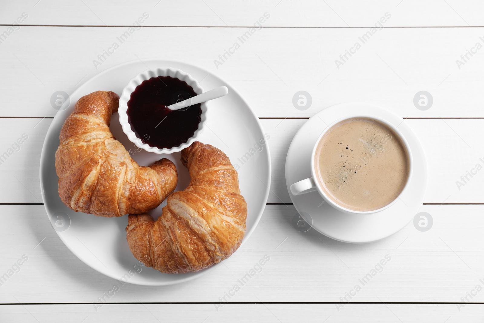 Photo of Fresh croissants, jam and coffee on white wooden table, flat lay. Tasty breakfast