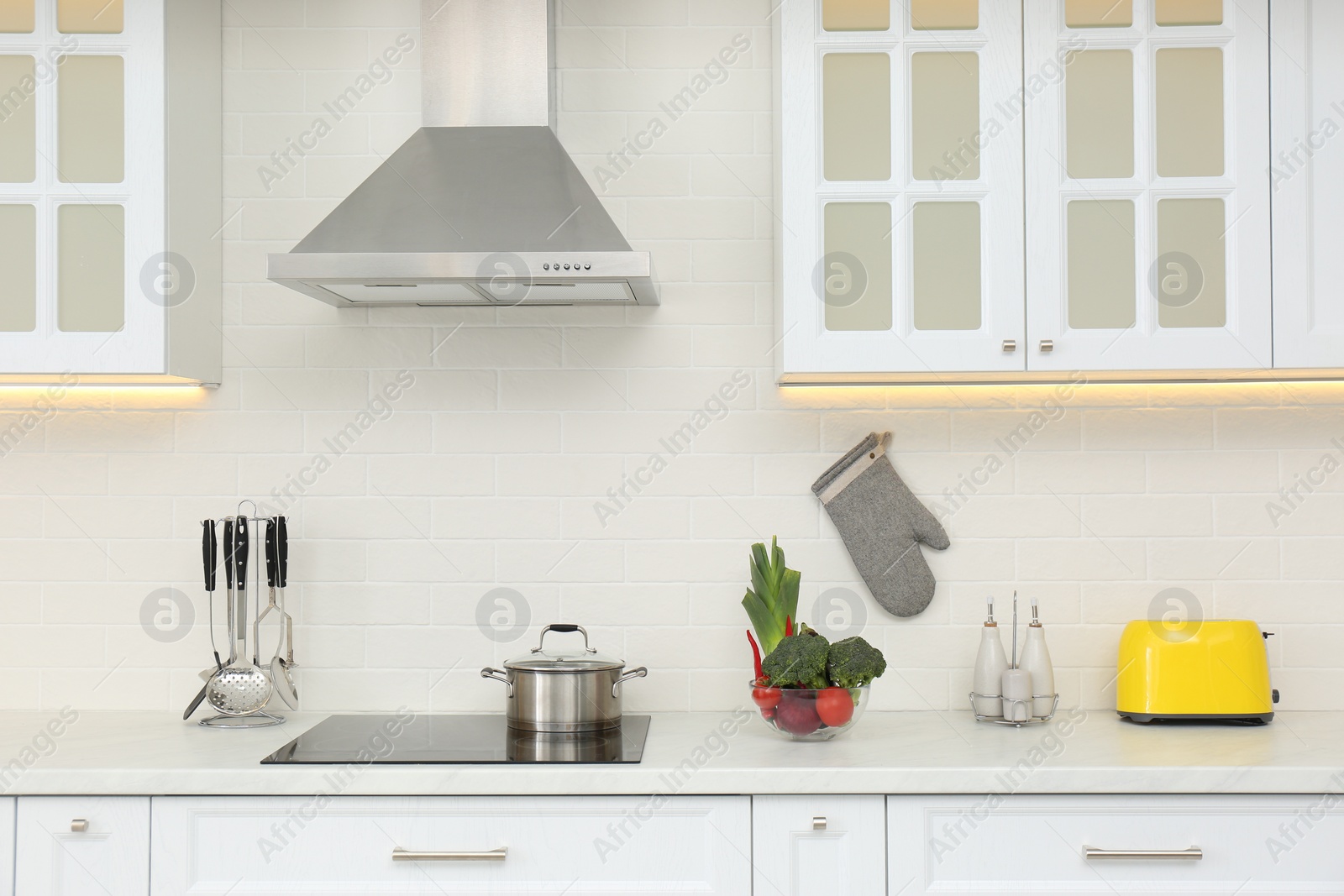 Photo of Pot on stove and fresh vegetables in modern kitchen