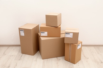 Photo of Stacked parcel boxes on floor against light wall