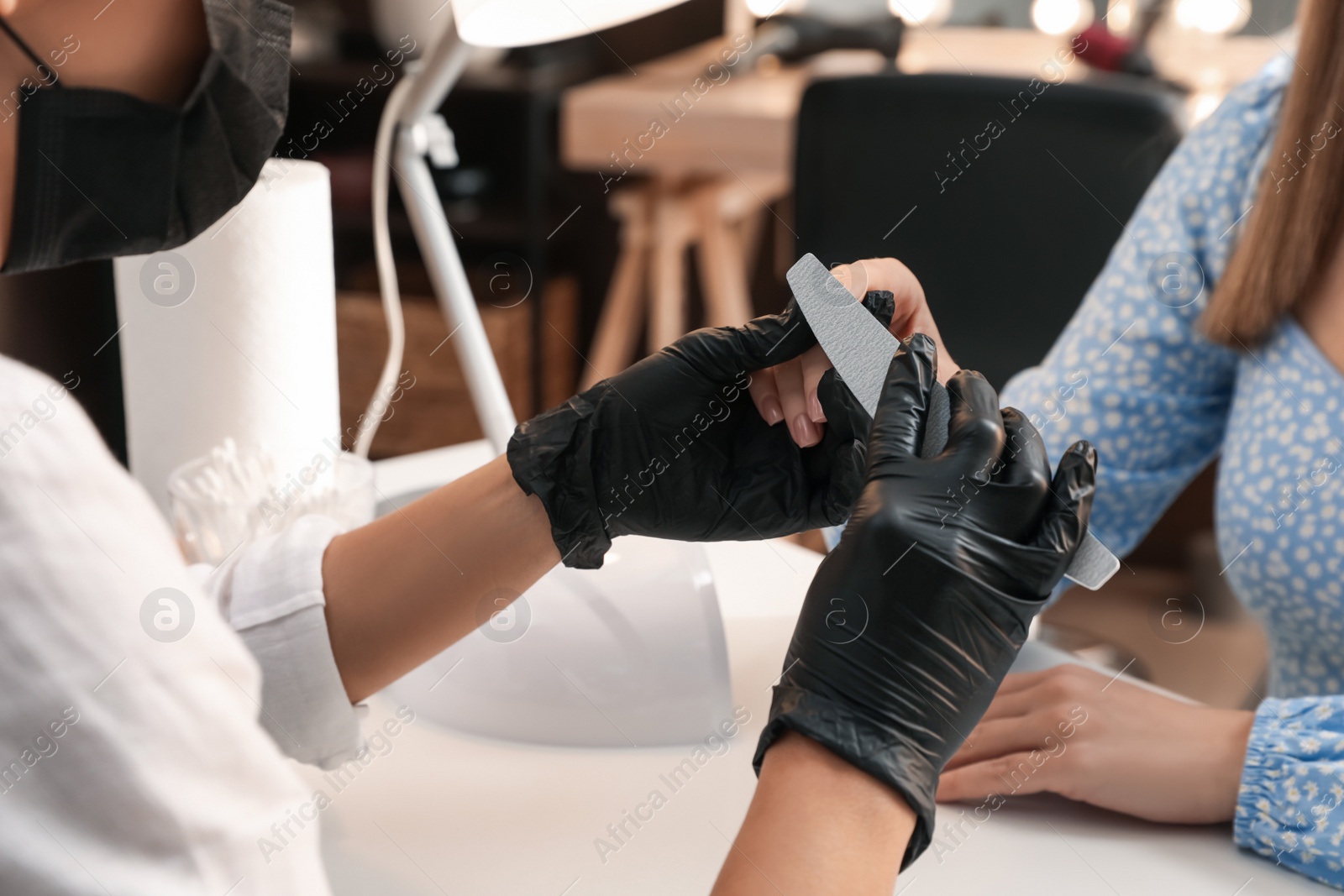 Photo of Professional manicurist working with client in salon, closeup. Beauty services during Coronavirus quarantine