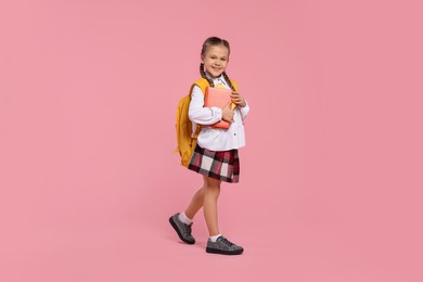 Photo of Happy schoolgirl with backpack and books on pink background