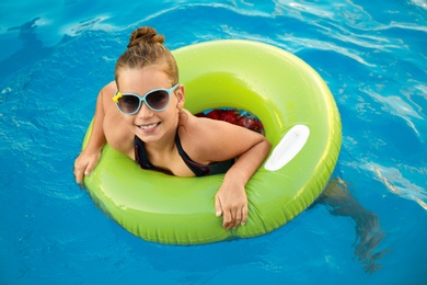 Photo of Happy little girl with inflatable ring in swimming pool