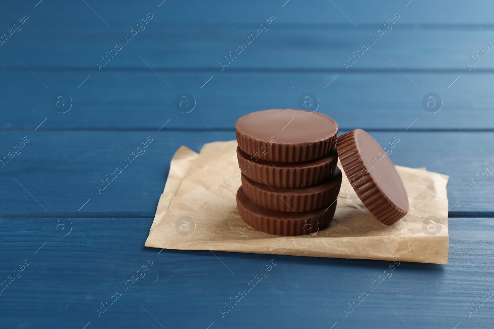 Photo of Delicious peanut butter cups on blue wooden table, space for text