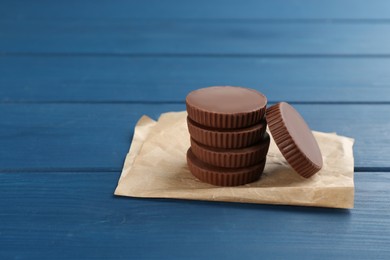 Delicious peanut butter cups on blue wooden table, space for text