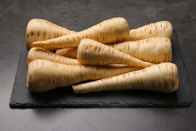 Photo of Delicious fresh ripe parsnips on black table